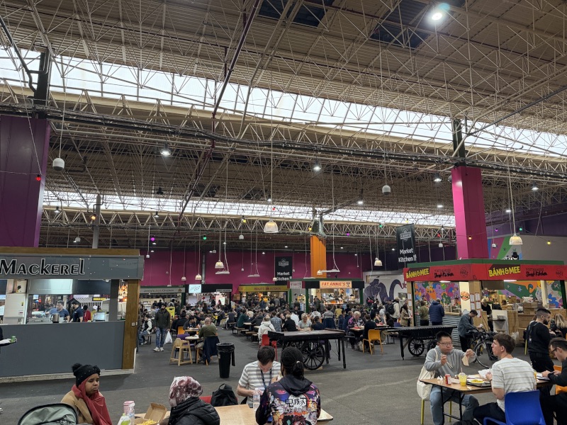 Photo of food stalls in the market. Stalls for mackerel and bánh mì are visible.